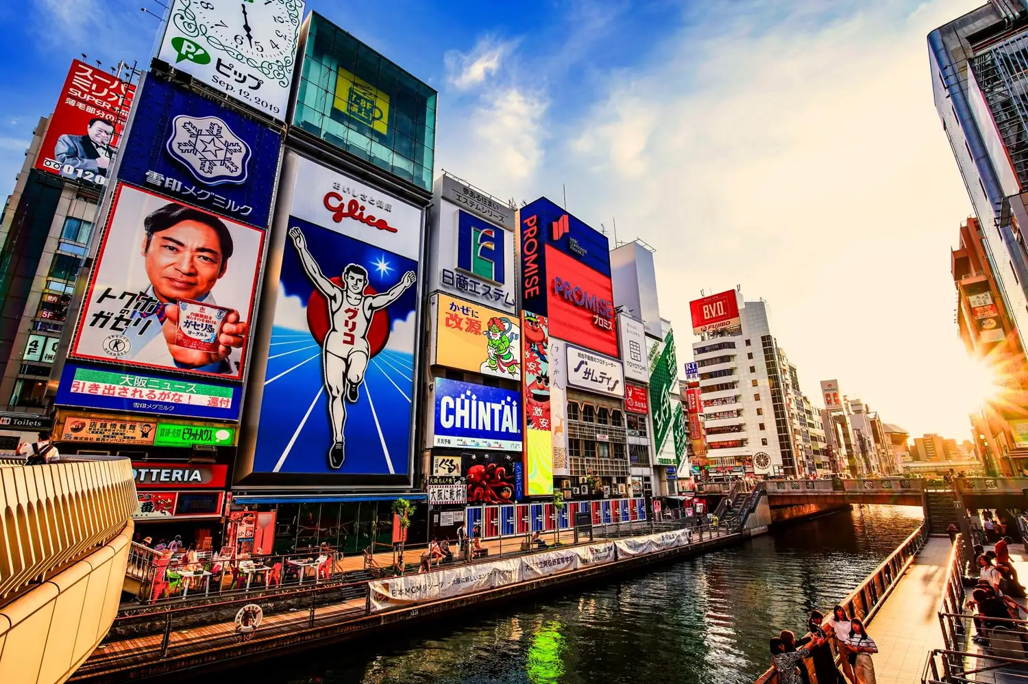 Illuminated neon signs and the Glico running man billboard along the Dotonbori canal in Osaka