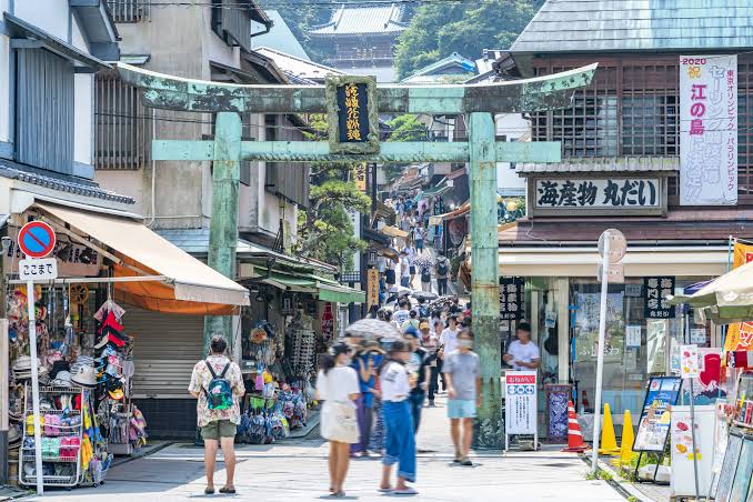 Tightly packed traditional wooden shops and street food stalls selling fresh seafood along the bustling Benzaiten Nakamise-dori approach street in Enoshima