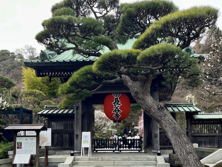 Small moss-covered stone shrine and ancient lanterns tucked into a quiet sacred backstreet corner in the Yanaka neighborhood