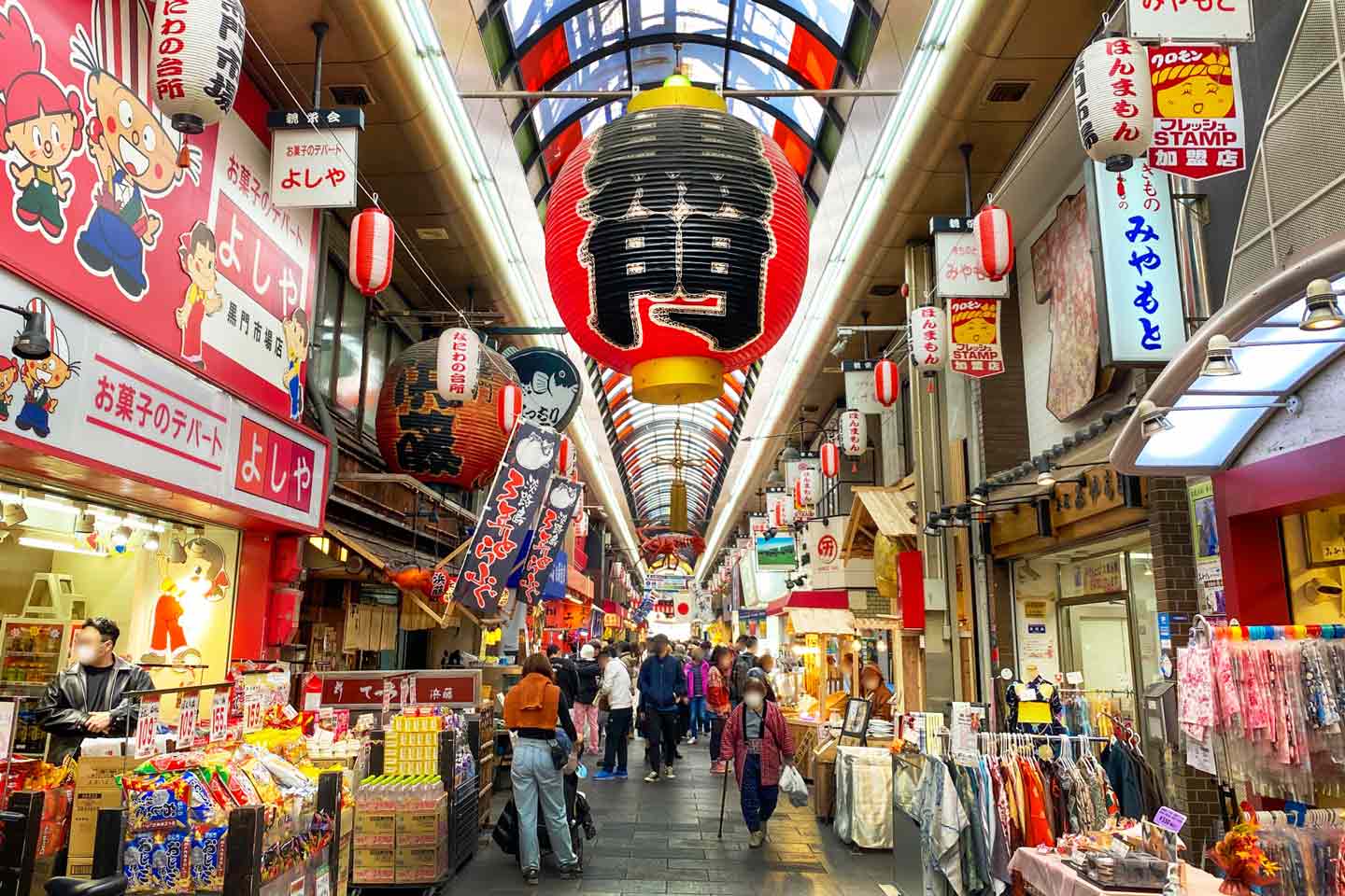 Fresh seafood and street food stalls lining the covered arcade of Kuromon Ichiba Market in Osaka