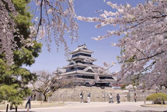 The black wooden exterior of Matsumoto Castle, known as the Crow Castle, against the Japan Alps in Nagano Prefecture