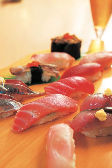 A master sushi chef pressing fresh seafood at a local sushiya counter