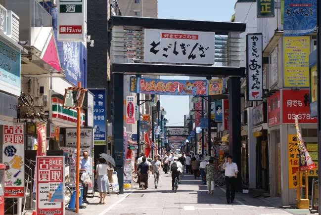 Crowds of local residents walking past traditional grocery stalls and croquette shops on the long pedestrian street of Togoshi Ginza shotengai